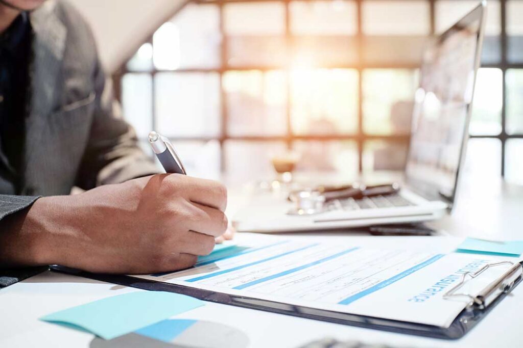 Family reviewing life insurance documents and beneficiary forms at a kitchen table.
